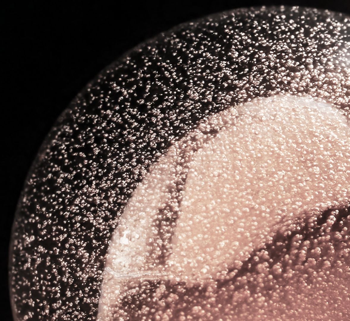 Texture macro montrant de nombreuses petites bulles disposées autour d’une surface rosée et arrondie