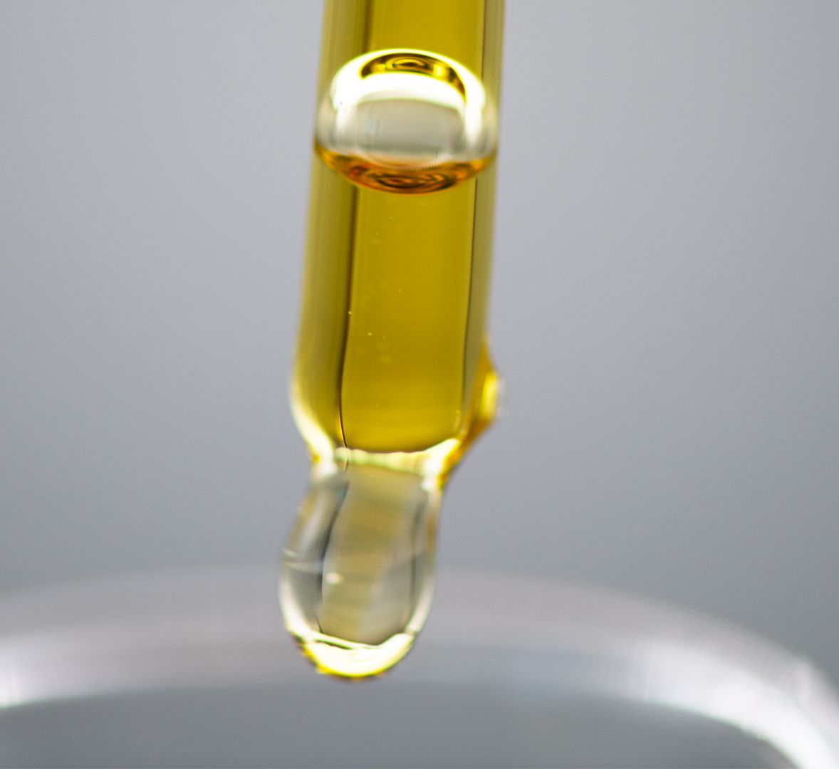 Liquide épais et translucide dans une pipette verticale sur fond clair