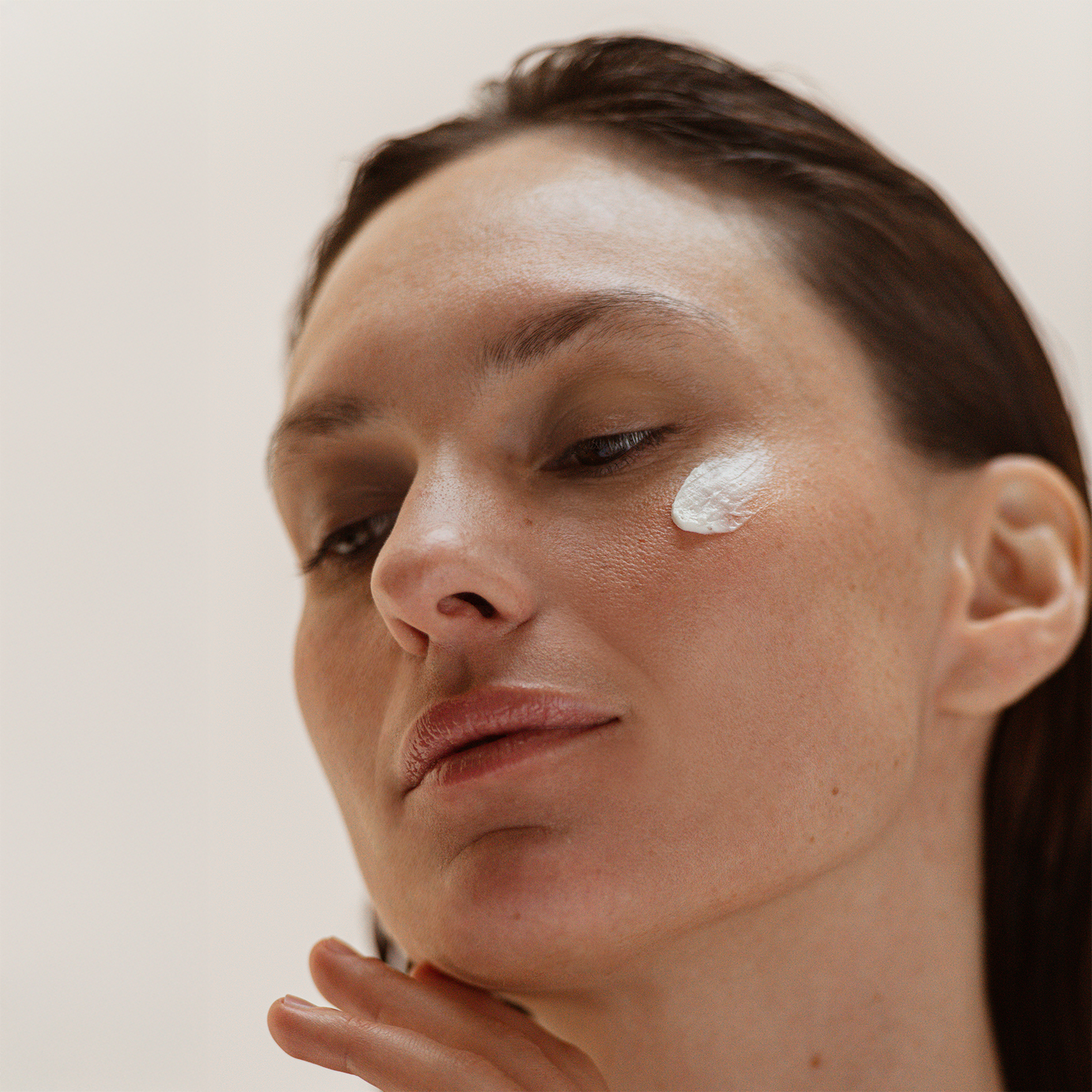 Visage d’une personne appliquant La Crème avec sa texture crème fouettée sur la zone sous l’œil