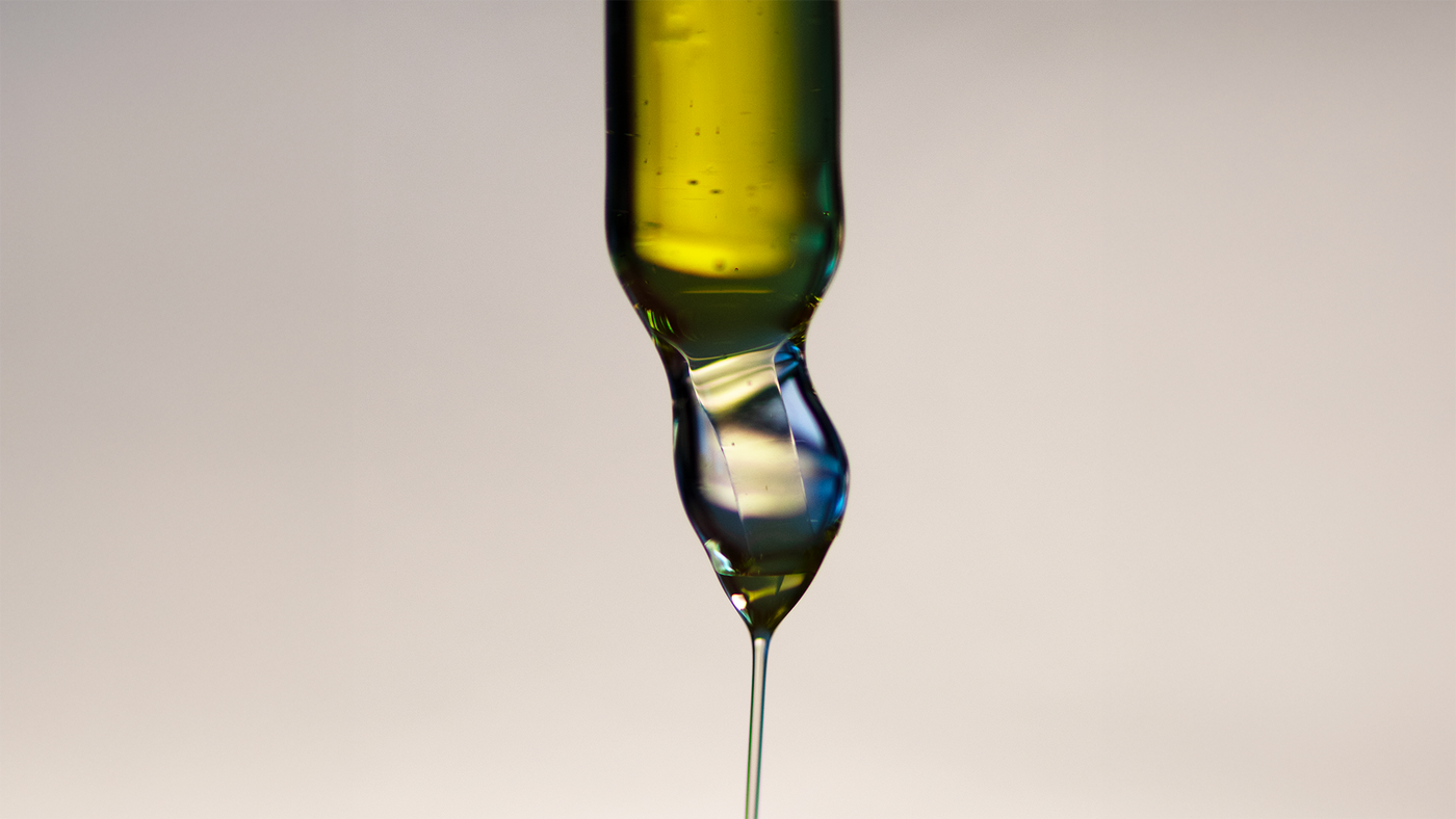 Texture épaisse qui s’écoule d’une pipette verticale sur fond beige