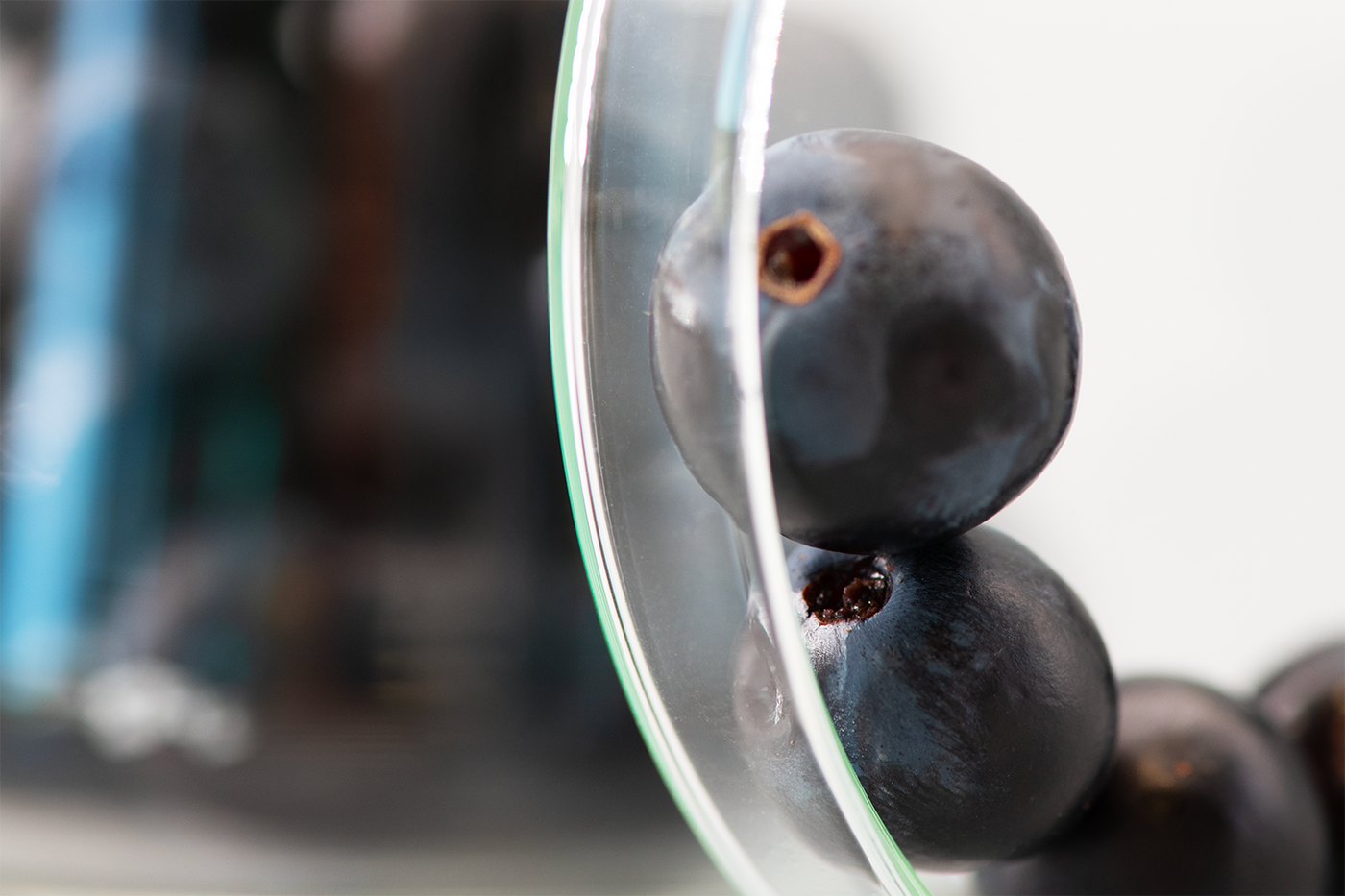 Raisins empilés contre une surface en verre, photographiés en macro avec un fond flou